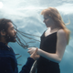 A man and a woman look at each other underwater.